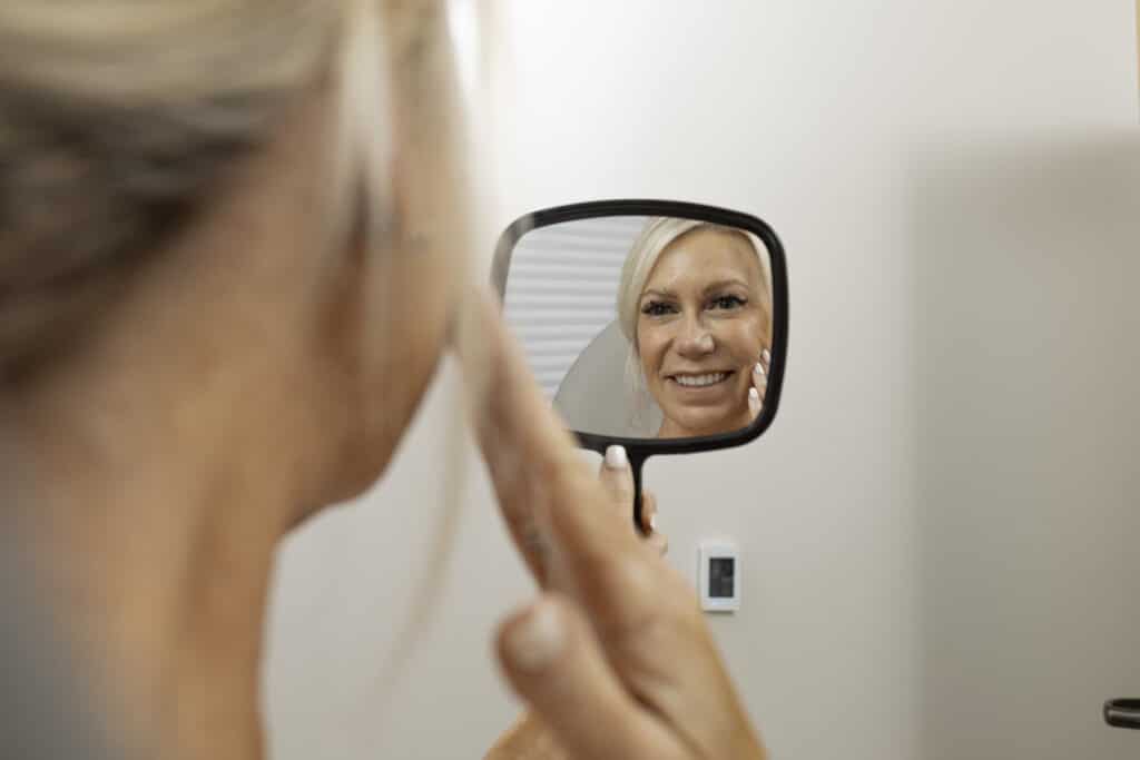 patient looking in the mirror and is very happy about facial volume